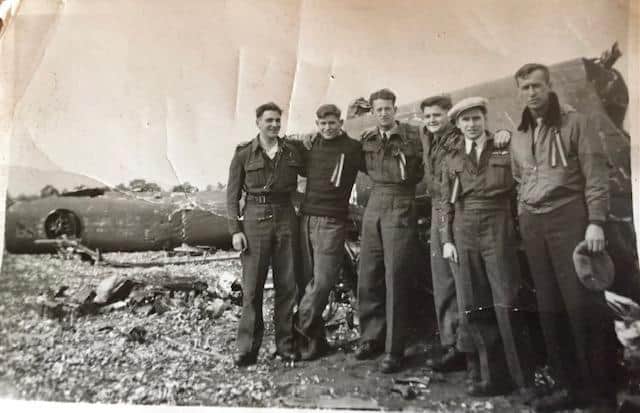 Geoff Wood, wearing a cap, Roger Dickerson, George Woodgate and three of the US Liberator crew posing together at the crash site near Gierle, Belgium
