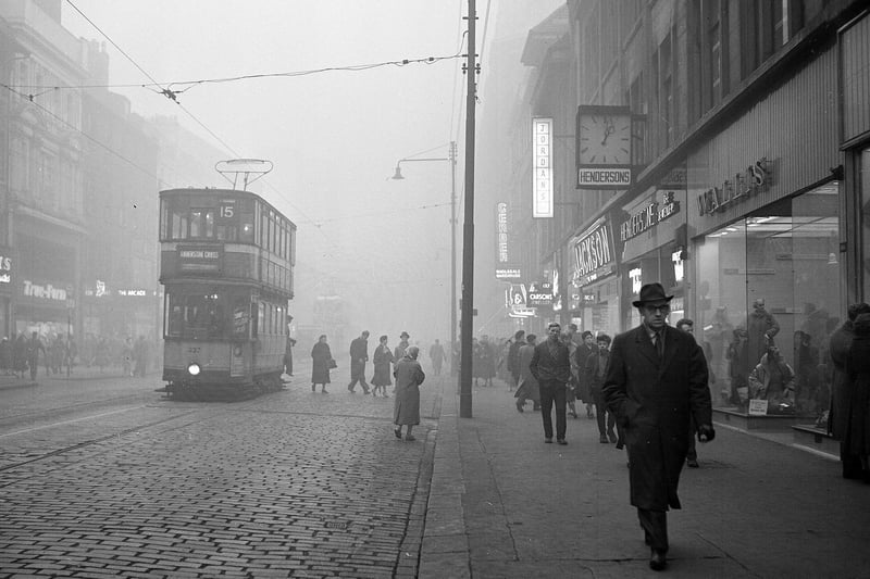 Fog in Argyle Street at lunchtime - Shop signs lit up as a tram heads along the road. 