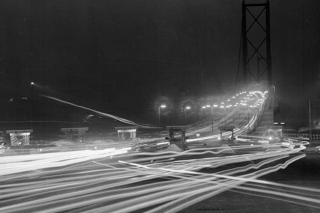 A time exposure photograph shows the lights of moving vehicles on the approach to the Forth Road Bridge in October 1964.