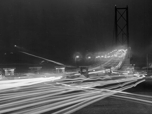 A time exposure photograph shows the lights of moving vehicles on the approach to the Forth Road Bridge in October 1964.
