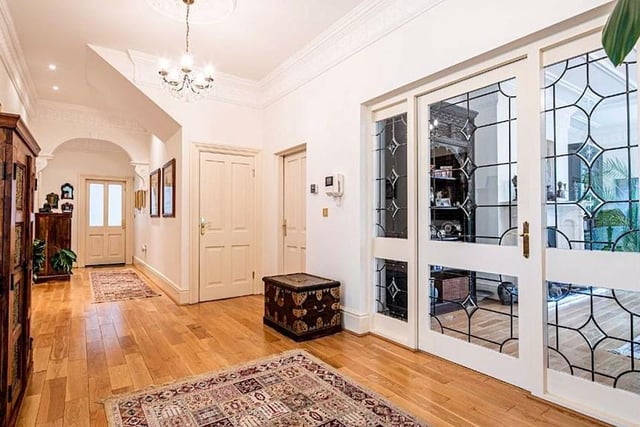 The apartment opens into a spacious entrance hall featuring a storage cupboard and oak flooring.