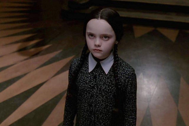 Braided pigtails, a pale foundation, black or purple eye shadow and black lipstick will give you the face of Wednesday Addams. Finish the look with a white collared black dress.