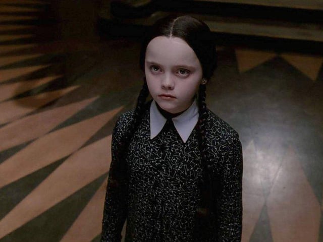 Braided pigtails, a pale foundation, black or purple eye shadow and black lipstick will give you the face of Wednesday Addams. Finish the look with a white collared black dress.