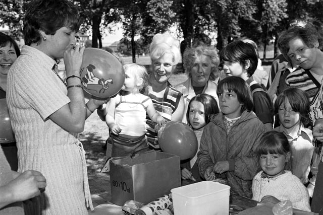 One of the stalls at Leith festival, held on Leith Links in June 1978. A helper blows up balloons as local children look on.