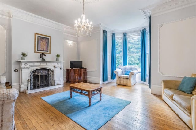 To the left of the reception hall is this delightful drawing room, with its high ceilings, open fireplace, oak flooring and imposing bay window. Comfortable and classy, it is infused with natural light.