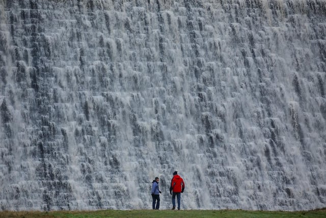 Hikers come to witness the rare waterfall at Ladybower Reservoir. High water levels mean water has begun to flow over the damn at Ladybower Reservoir, Peak District, in January  2016.