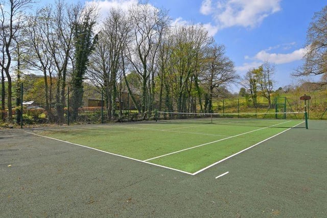 The tarmac tennis court is one of the features of the grounds, which include well-kept lawned gardens with terraces, all with beautiful surroundings and next to a stream.