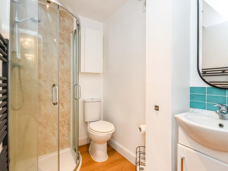 The ensuite from the third bedroom has a heated towel rail, panelled walls, extractor fan, LVT flooring and a handy built-in cupboard. There is a three piece suite with a single shower, low-flush WC and a vanity sink with a mixer tap.
