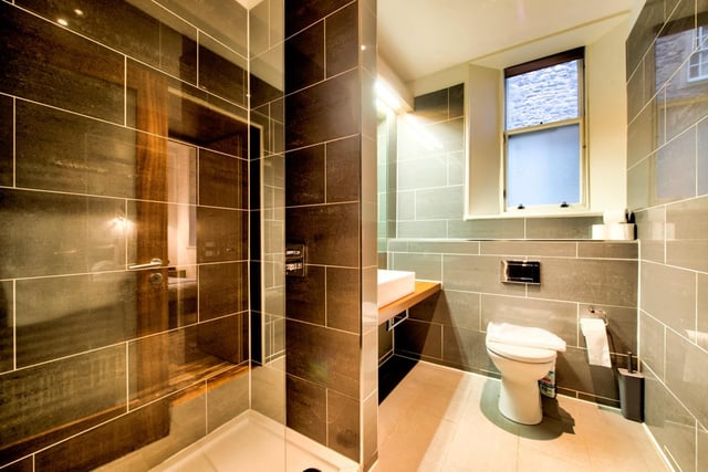 The bathroom comes fully-equipped with a standing shower and bath, as well as a toilet and a sink, with modern tiling and a window for ventilation.