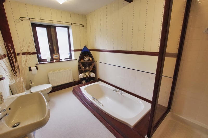 Featuring a double-glazed stone mullion window, bath, shower cubicle, wash hand basin, toilet and ceiling beam.