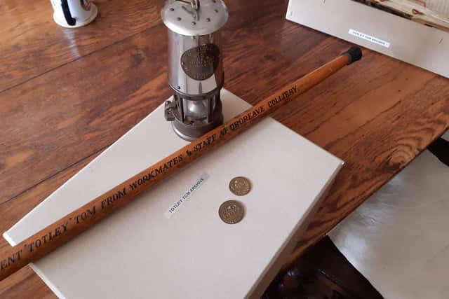 Tom's memorabilia including an engraved pit lamp and deputy staff - a walking stick which was presented to him. You can also see pit tokens and a box of his papers.