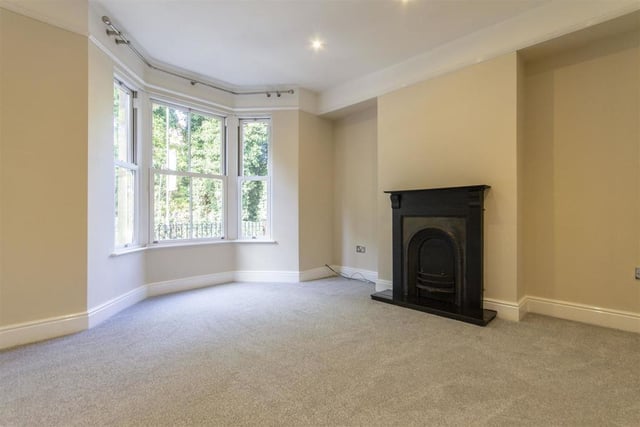An ornamental fireplace and bay window are focal points of this generously sized reception room.