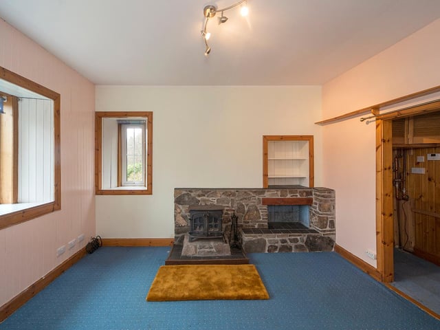 The living room boasts a wood-burning stove and windows on two sides