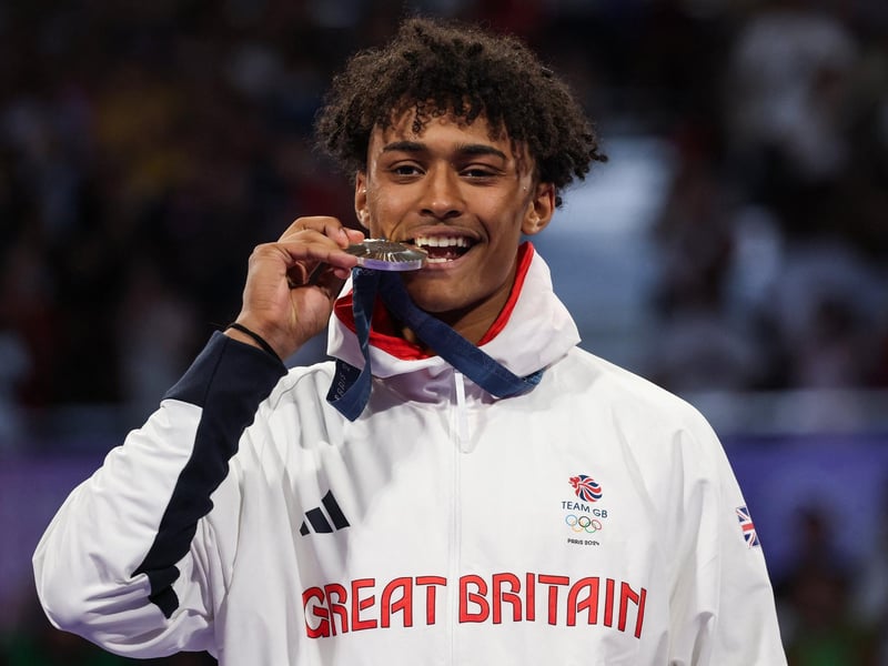 Another medallist, Cunningham bites his medal on the podium after winning silver for the taekwondo men's +80kg.