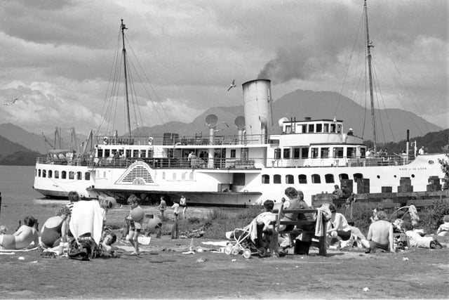 Holidaymakers enjoy the sun in Balloch as the Maid of the Forth paddle steamer passes by in Loch Lomond, July 1972.