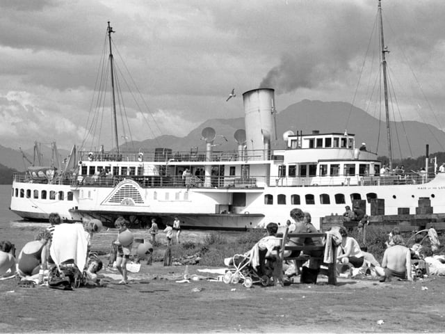 Holidaymakers enjoy the sun in Balloch as the Maid of the Forth paddle steamer passes by in Loch Lomond, July 1972.