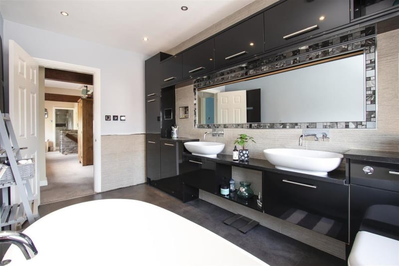 The first-floor family bathroom boasts a freestanding bath and his and hers sink and a stylish shower room.