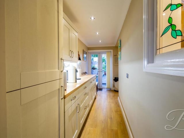 This narrow, elongated section is part of the quirkily-shaped kitchen. At one end are patio doors leading to the back garden, while at the other is a door leading to the front of the property.