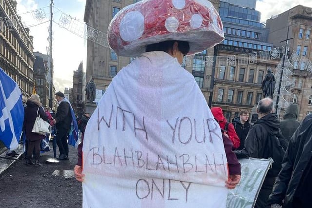 An activist with a mushroom top on their head and a sign which reads: "With your blah blah blah only mushrooms will survive."