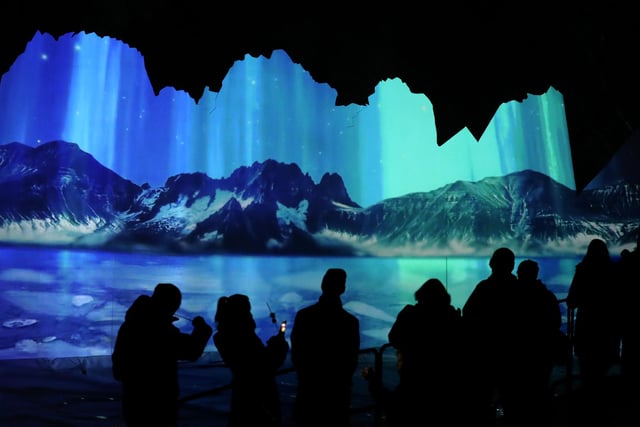 Members of the public are silhouetted against an animation of of the Northern Lights which was projected onto an iceberg installation at the launch of Edinburgh Zoo's Christmas Nights.