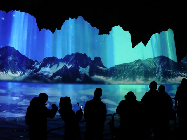 Members of the public are silhouetted against an animation of of the Northern Lights which was projected onto an iceberg installation at the launch of Edinburgh Zoo's Christmas Nights.