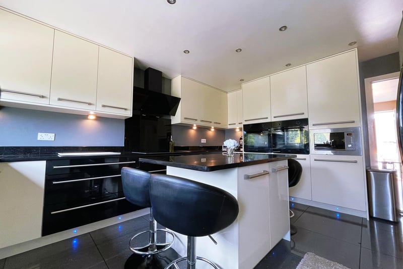 The kitchen is fully fitted with a range of matching eye level and base units with surfaces over. It is equipped with a breakfast island with storage, a sink and drainer, induction hob and double oven, extractor fan, integrated microwave, a dishwasher, a central heating radiator and a front facing double glazed window.