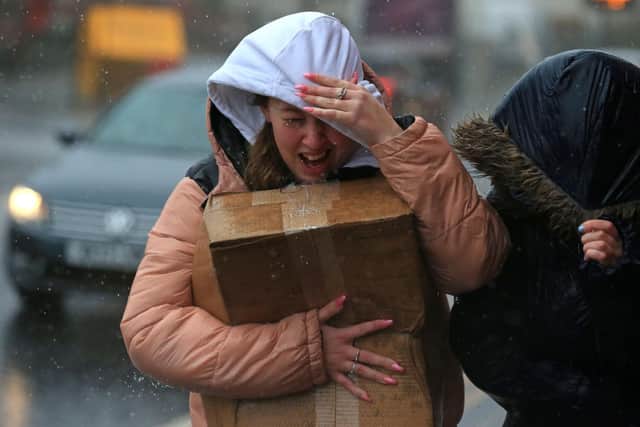 A woman tries to protect herself from the high winds and rain in Sheffield (Photo by LINDSEY PARNABY/AFP via Getty Images)