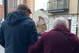 This heartwarming photo shows an elderly couple walking arm-in-arm - and just happen to perfectly frame 'The Snog' by Pete McKee.