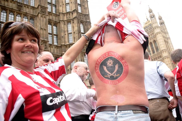 A fan shows off his back tattoo of the club crest