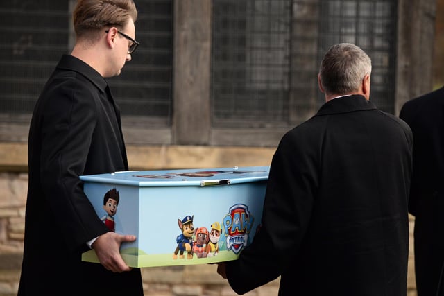 Two pall bearers carry Keigan's tiny coffin.