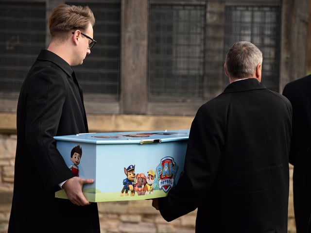 Two pall bearers carry Keigan's tiny coffin.