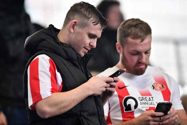 Two Sunderland fans on their phones at Fratton Park ahead of the clash between Sunderland and Portsmouth.