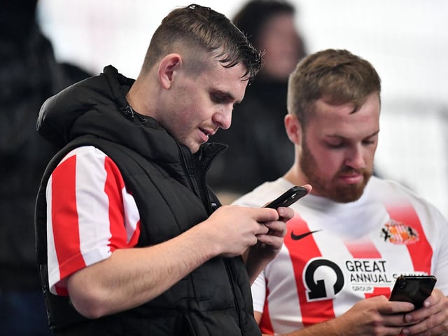 Two Sunderland fans on their phones at Fratton Park ahead of the clash between Sunderland and Portsmouth.
