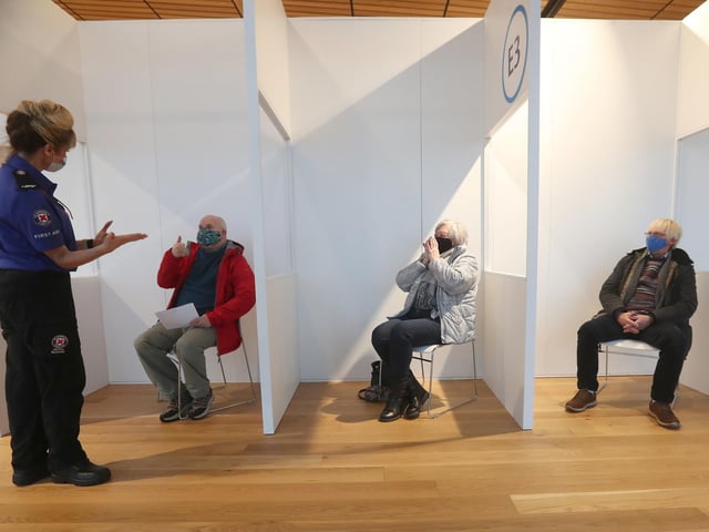 A St Andrews First Aider chats with (left to right) James Logan, Sylvia Campbell and Michael Maddocks as they sit in a waiting area after receiving their coronavirus vaccine.