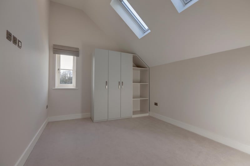 Bedroom two has two electrically operated Velux roof windows, recessed lighting, TV/aerial point, data point and under floor heating. To one wall, there’s a range of fitted furniture incorporating long hanging and shelving.