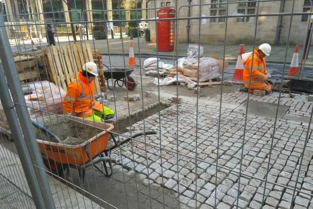 Workers re-laying cobbles on Surrey Street.