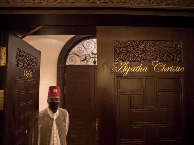 An employee (mask-clad due to the COVID-19 coronavirus pandemic) of the Old Cataract Hotel stands through the door of the suite where British crime fiction writer Dame Agatha Christie is believed to have stayed while writing her 1937 novel "Death on the Nile",