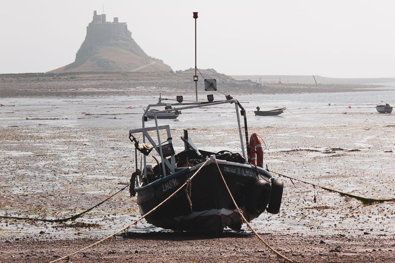 A boat moored with Lindisfarne Castle on Holy Island in the background.
