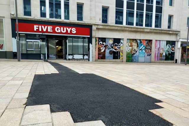 The slab paving on The Moor, Sheffield, has been replaced by black asphalt following gas works for a new Five Guys restaurant.