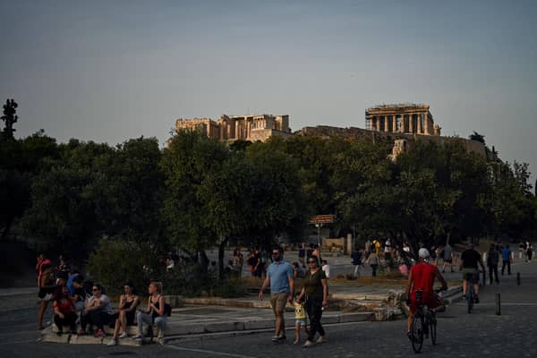 People walk with in background the ancient Temple of Parthenon a(Photo by ARIS MESSINIS/AFP via Getty Images)