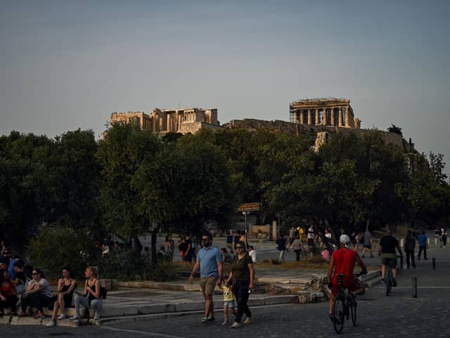People walk with in background the ancient Temple of Parthenon a(Photo by ARIS MESSINIS/AFP via Getty Images)