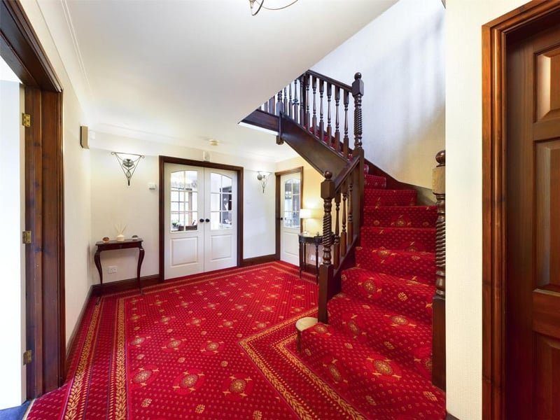 Fron door with stained glass panel, two wall light points, under-stairs storage cupboard, stairs to first floor leading.