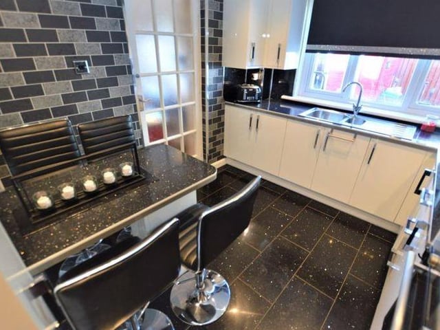 The kitchen is a modern, high gloss fitted kitchen with a range of base and wall mounted units and is completed by a breakfast bar