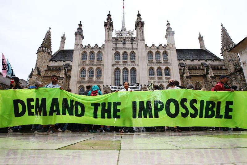 Protesters from Extinction Rebellion hold up a banner outside the Guildhall during a protest on August 22, 2021 in London, England. (Photo by Hollie Adams/Getty Images)