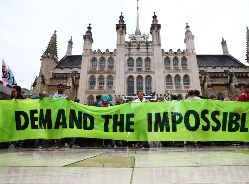 Protesters from Extinction Rebellion hold up a banner outside the Guildhall during a protest on August 22, 2021 in London, England. (Photo by Hollie Adams/Getty Images)