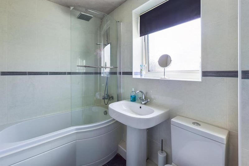 The family bathroom boasts a white, three-piece suite including P-shaped bath with shower over.