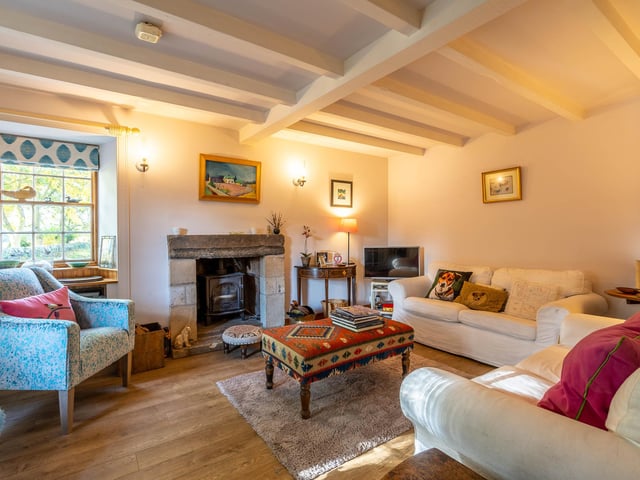 The living room boasts a wood-burning stove, set in a recessed original fireplace