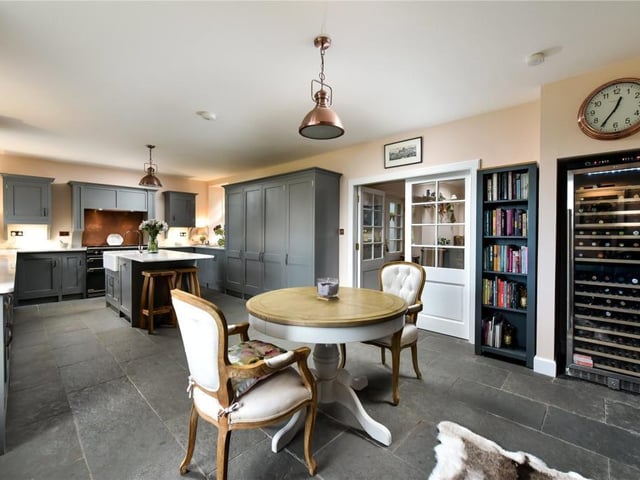 The open plan dining kitchen has hand made painted units, flagstone flooring, marble worktops, a central island, gas range cooker, and warming wood burning stove.
