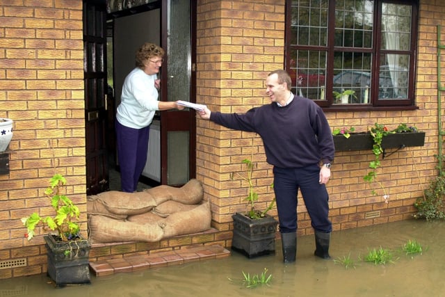 ...Even rising floodwater did not stop postie Mark Smith delivering Margaret Child her mail in Sykehouse, Doncaster in 2000
