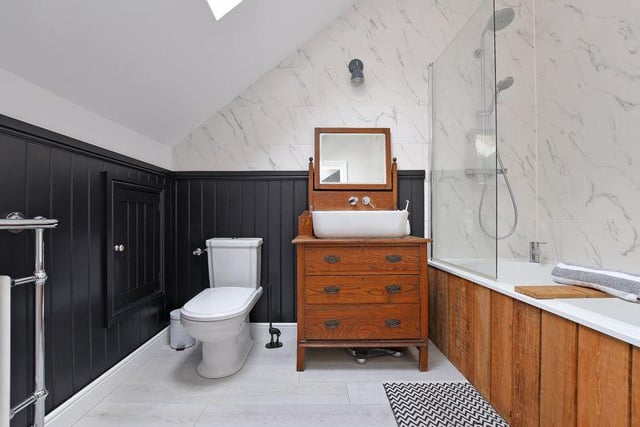 The main bedroom's en-suite bathroom contains an oversized bath, a shower, an oak washstand, a column radiator with chrome towel rail, a Velux window and storage in the eaves.